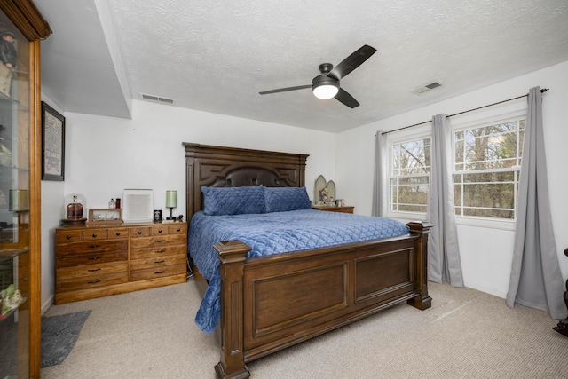 bedroom with light colored carpet, visible vents, and a textured ceiling