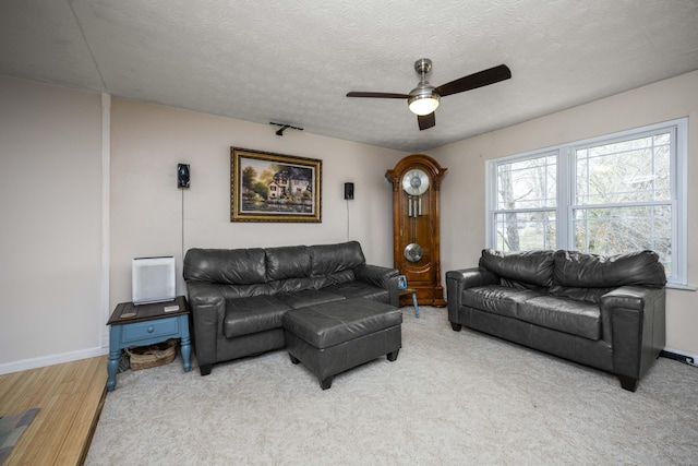 carpeted living room featuring ceiling fan, baseboards, and a textured ceiling