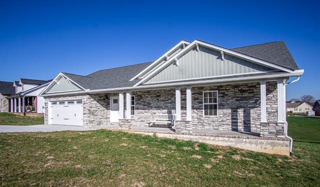 view of front of property with a front lawn, covered porch, and a garage