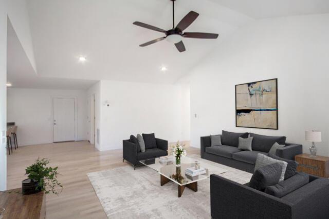 living room with ceiling fan, light hardwood / wood-style flooring, and high vaulted ceiling