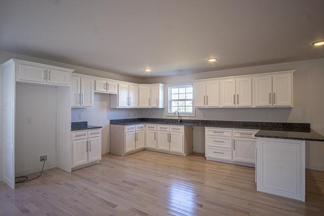 kitchen with white cabinets, light hardwood / wood-style flooring, and sink