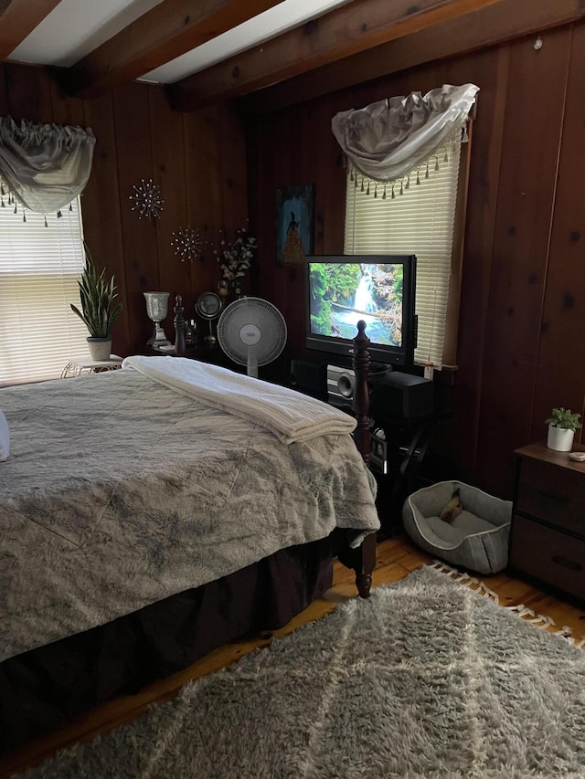 bedroom featuring wood walls, beamed ceiling, and light hardwood / wood-style floors