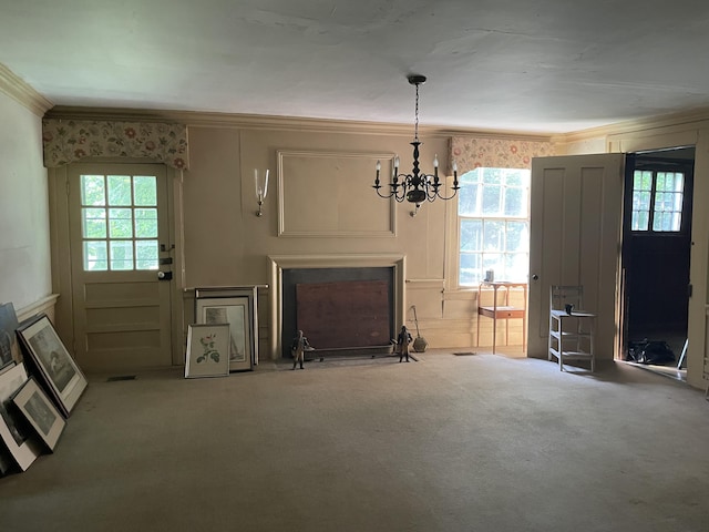 unfurnished living room with carpet floors, an inviting chandelier, and ornamental molding