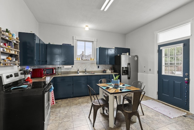 kitchen with sink, light tile patterned floors, blue cabinetry, tasteful backsplash, and stainless steel appliances