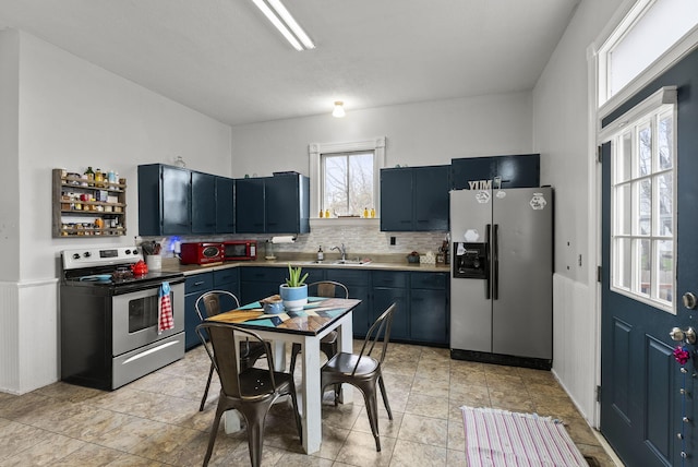 kitchen featuring backsplash, blue cabinetry, sink, and appliances with stainless steel finishes