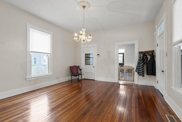 unfurnished room with a notable chandelier and dark wood-type flooring