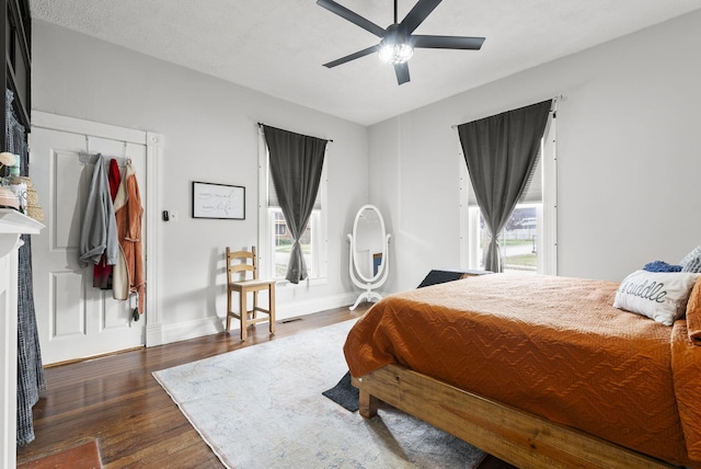 bedroom with dark hardwood / wood-style floors, ceiling fan, a textured ceiling, and multiple windows