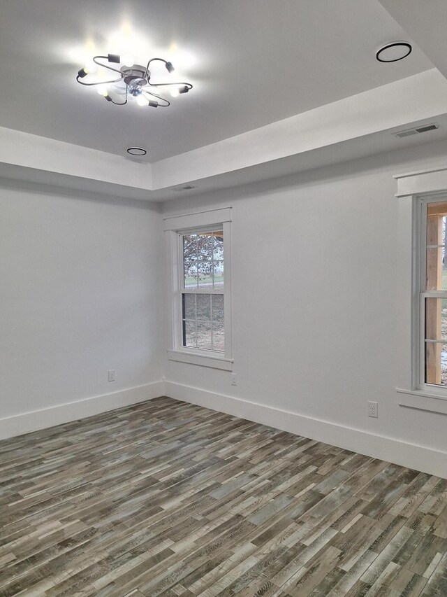 unfurnished room with dark hardwood / wood-style flooring, a raised ceiling, and a notable chandelier