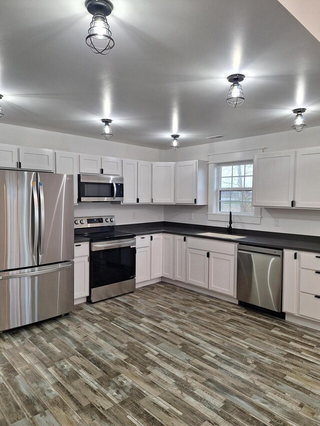 15 David St, Flemingsburg, KY 41041 - kitchen featuring appliances with stainless steel finishes, dark countertops, dark wood-style floors, and white cabinetry