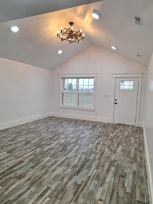 unfurnished living room featuring dark wood-type flooring, vaulted ceiling, and an inviting chandelier