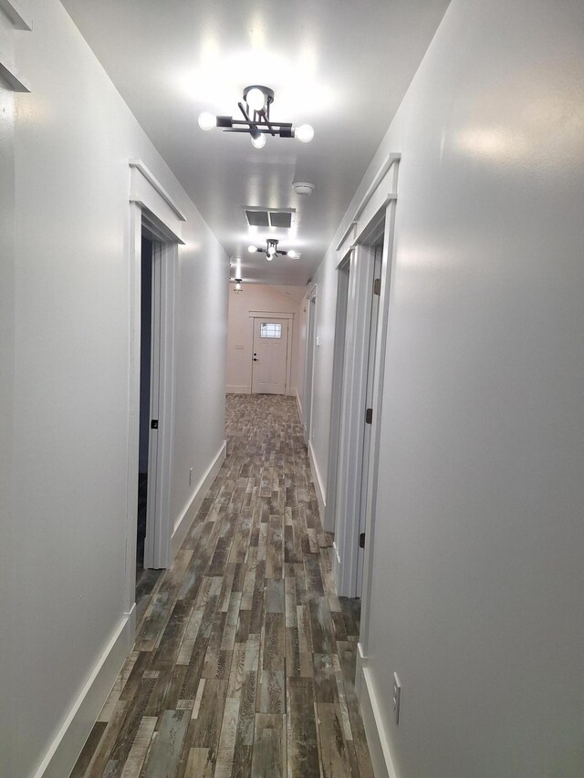 corridor featuring dark hardwood / wood-style floors and an inviting chandelier