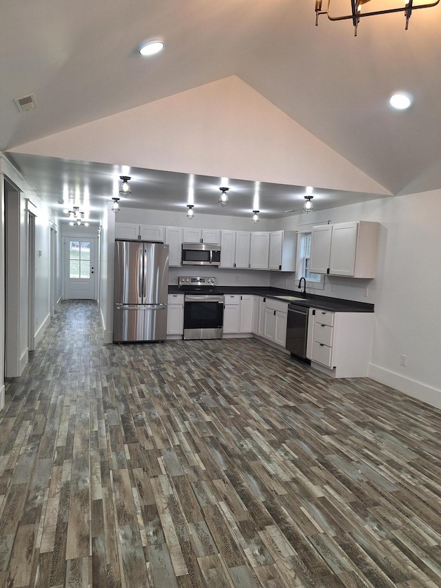 15 David St, Flemingsburg, KY 41041 - kitchen with stainless steel appliances, vaulted ceiling, dark countertops, dark wood-style floors, and white cabinetry