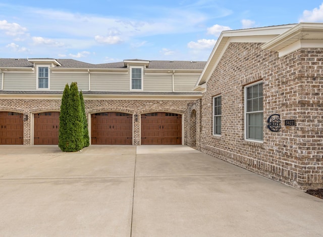 view of side of home with a garage, driveway, and brick siding