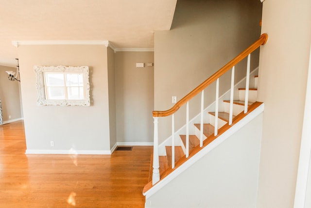 staircase featuring wood-type flooring and crown molding