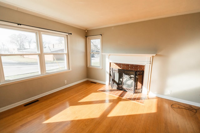 unfurnished living room featuring wood-type flooring, a fireplace, and ornamental molding