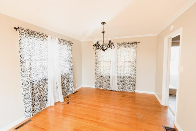 unfurnished dining area with wood-type flooring, ornamental molding, and a notable chandelier