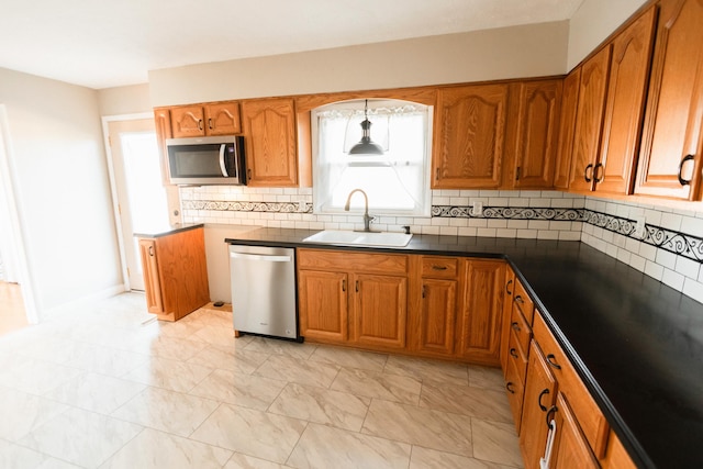 kitchen with pendant lighting, sink, stainless steel appliances, and tasteful backsplash