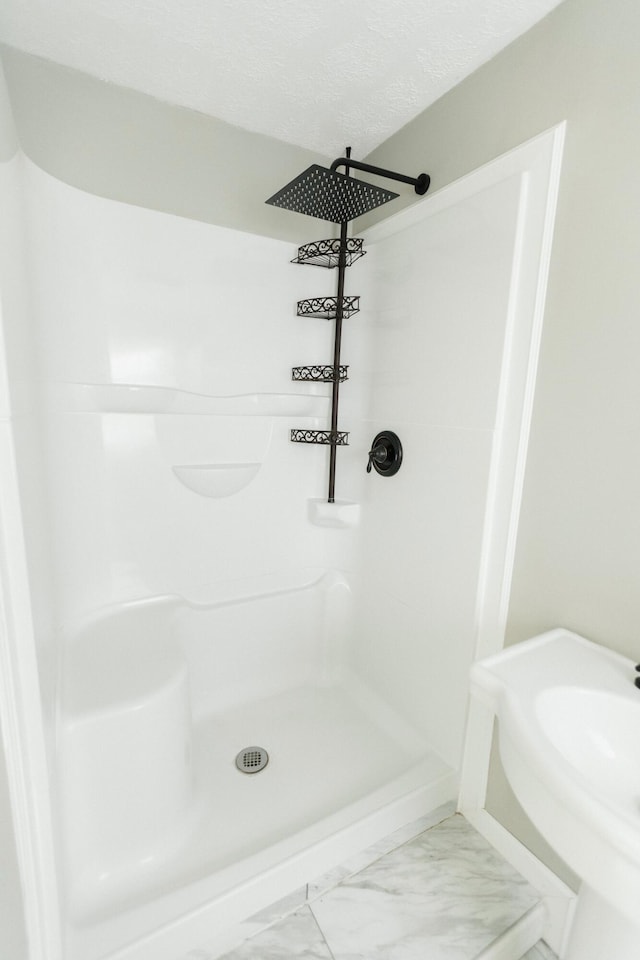 bathroom featuring a textured ceiling and walk in shower