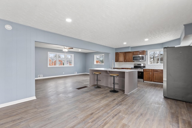 kitchen featuring a kitchen breakfast bar, a center island, stainless steel appliances, and hardwood / wood-style flooring