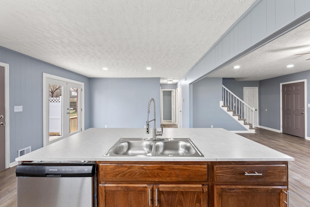 kitchen featuring dishwasher, light hardwood / wood-style floors, sink, and an island with sink