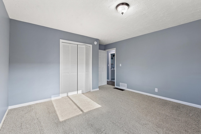 unfurnished bedroom featuring a closet, carpet, and a textured ceiling