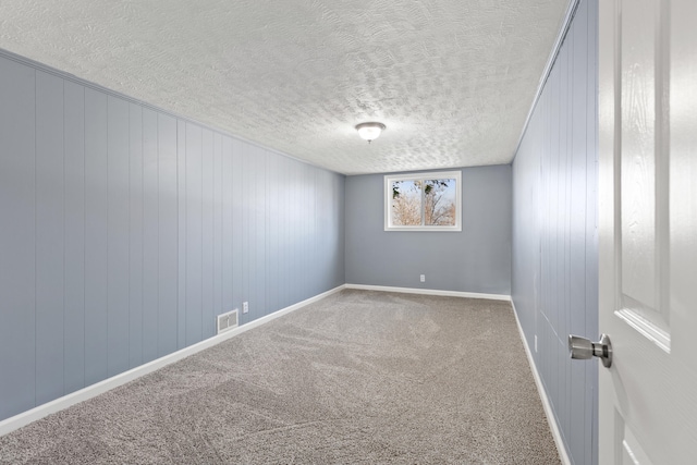 carpeted empty room with wood walls and a textured ceiling