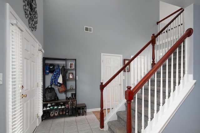 stairs featuring tile patterned floors and a high ceiling