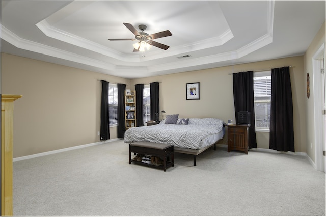 bedroom featuring ceiling fan, light carpet, a tray ceiling, and multiple windows