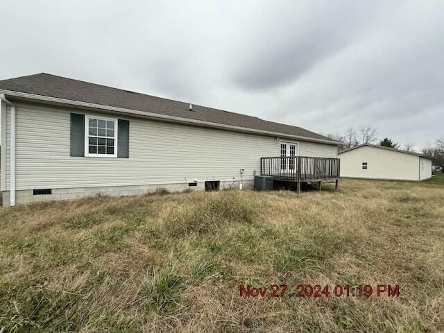 rear view of house featuring a deck, central AC unit, and a lawn