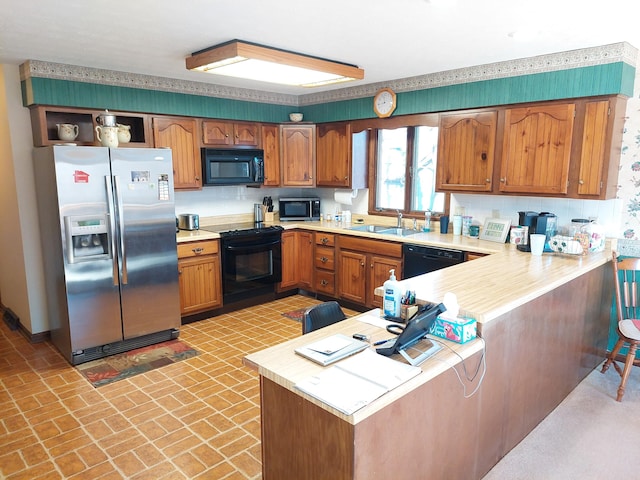 kitchen featuring kitchen peninsula, sink, tasteful backsplash, and black appliances