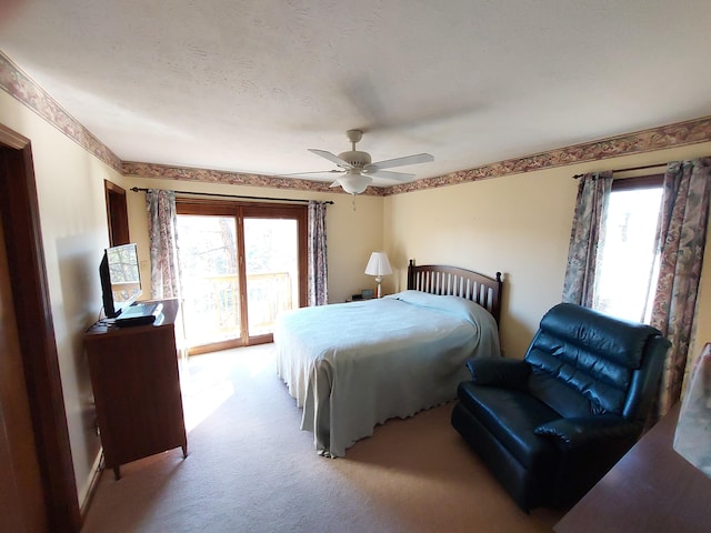 carpeted bedroom with a textured ceiling, access to outside, multiple windows, and ceiling fan