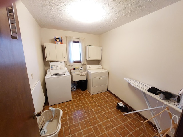 laundry room featuring sink, cabinets, separate washer and dryer, and a textured ceiling