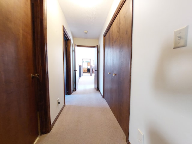 hall featuring a textured ceiling and light carpet