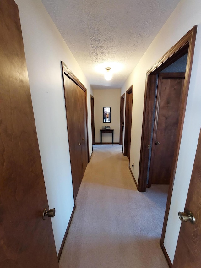 hallway featuring light carpet and a textured ceiling