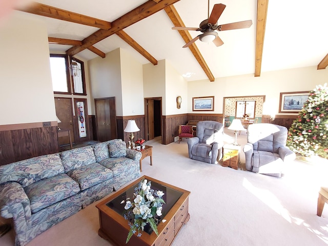 carpeted living room with beamed ceiling, ceiling fan, high vaulted ceiling, and wooden walls