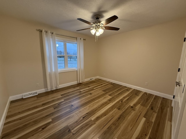 spare room featuring a textured ceiling, dark hardwood / wood-style floors, ceiling fan, and a water view