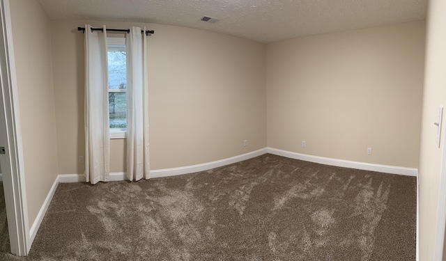 unfurnished room with a textured ceiling and dark colored carpet