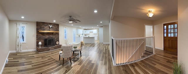 living room featuring ceiling fan, hardwood / wood-style floors, and a fireplace