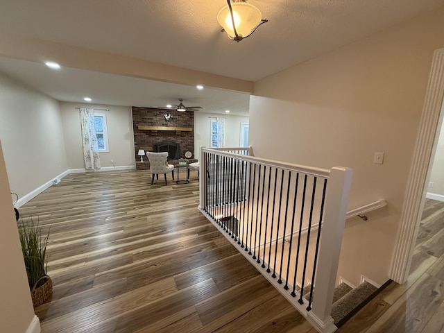 staircase featuring hardwood / wood-style flooring, a fireplace, and ceiling fan