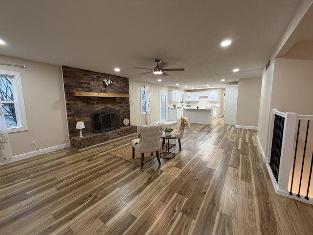 living room with hardwood / wood-style flooring, ceiling fan, and a fireplace