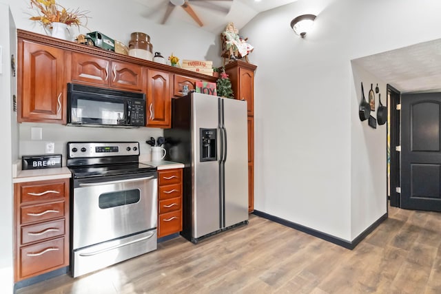 kitchen featuring vaulted ceiling, stainless steel appliances, and light hardwood / wood-style flooring