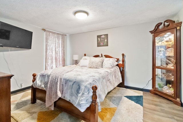 bedroom featuring light hardwood / wood-style floors and a textured ceiling