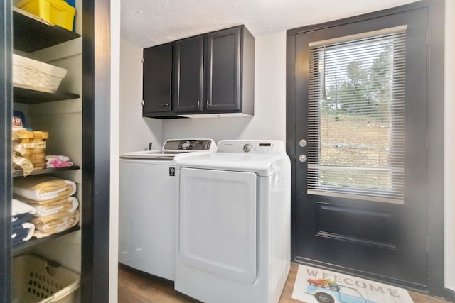 laundry room with cabinets, wood-type flooring, a textured ceiling, and separate washer and dryer