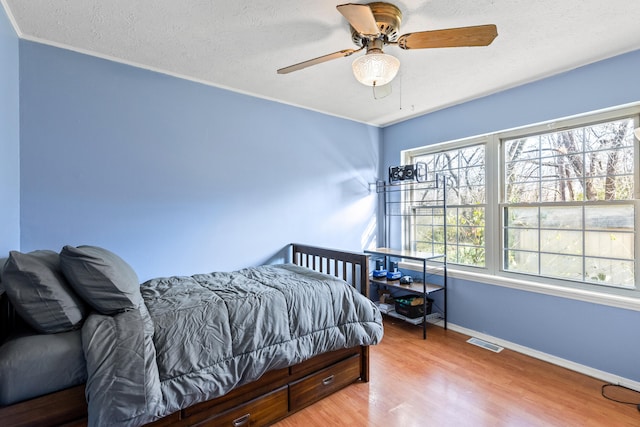 bedroom featuring ceiling fan, hardwood / wood-style floors, crown molding, and a textured ceiling