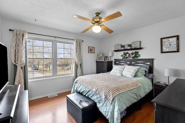 bedroom with a textured ceiling, ceiling fan, and dark hardwood / wood-style floors