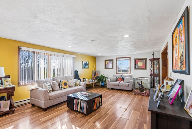 living room featuring light hardwood / wood-style flooring, a textured ceiling, and a baseboard heating unit