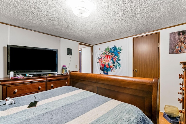 bedroom with ornamental molding, a textured ceiling, and hardwood / wood-style flooring