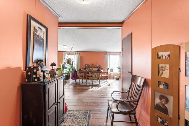 corridor featuring hardwood / wood-style floors, a textured ceiling, and ornamental molding