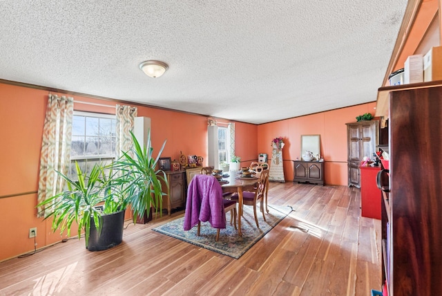 dining room featuring a textured ceiling, light wood-type flooring, and crown molding