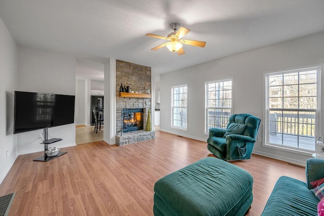 living room featuring a fireplace, ceiling fan, and light hardwood / wood-style flooring